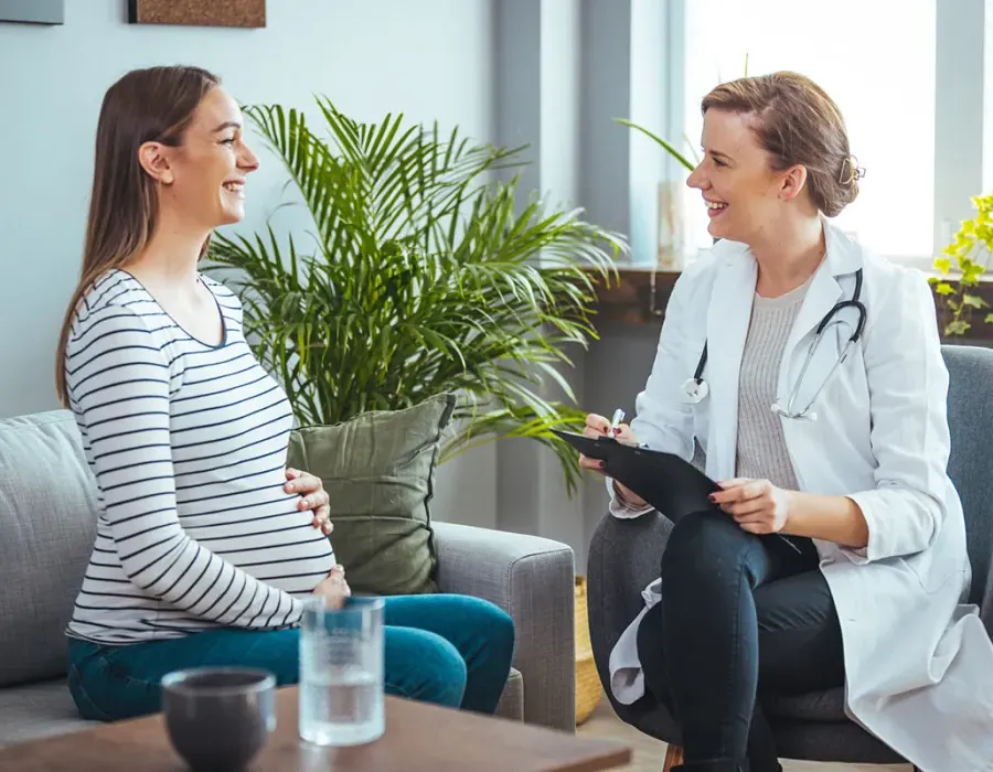 Women's health nurse practitioner smiling with pregnant patient